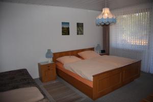 um quarto com uma cama com uma estrutura de madeira e uma mesa de cabeceira em Haus Grüne Insel - Ferienwohnungen em Altenau