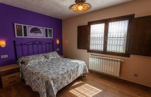 a bedroom with a bed and a purple wall at Apartamentos Vega Rodiles la huerta in Villaviciosa