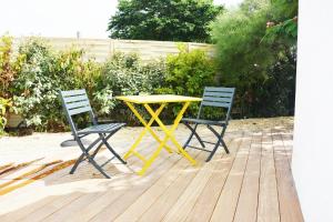 a yellow table and two chairs on a patio at Logis Hôtel La Chaize in Noirmoutier-en-l'lle