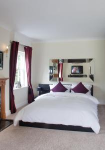 a bedroom with a large white bed with red curtains at Sturmer Hall Hotel and Conference Centre in Haverhill