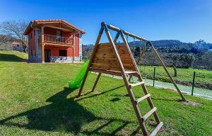 Une balançoire en bois est installée dans une cour avec une maison. dans l'établissement Apartamentos Vega Rodiles el campu, à Villaviciosa