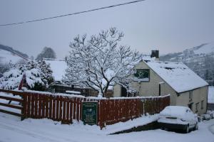 a yard covered in snow with a fence and a house at The Tanners Arms in Devynock