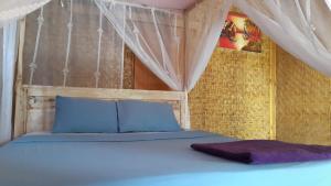 een slaapkamer met een bed met blauwe kussens bij Friend House SURF & STAY in Airsatang