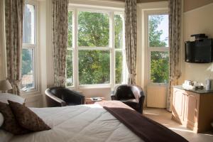 a bedroom with a bed and two chairs and a window at The Sheldon B&B - FREE private parking in Eastbourne