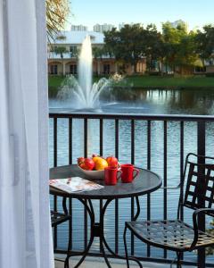 a table with a bowl of fruit on a balcony with a fountain at Inn at Pelican Bay in Naples