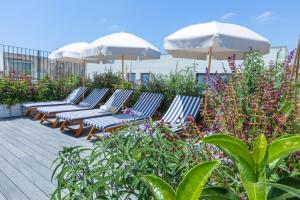 
a row of lounge chairs with umbrellas on a patio at Hotel Saul in Tel Aviv
