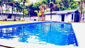 a swimming pool with blue water in front of a house at Morada do Sol Cambury in Camburi