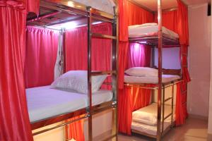 a group of bunk beds in a room with red curtains at Sunset Backpackers Hostel in Orchha