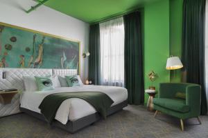 a green bedroom with a bed and a green chair at Angad Arts Hotel in Saint Louis