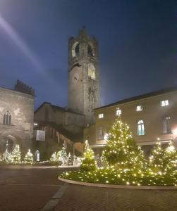 un edificio con árboles de Navidad frente a una torre del reloj en Belle Arti, en Bérgamo