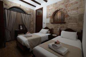 two beds in a room with a stone wall at Hanna Koumi Boutique Hotel in Kormakiti