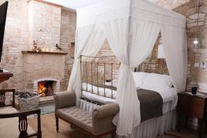 een slaapkamer met een hemelbed en een open haard bij Hanna Koumi Boutique Hotel in Kormakiti