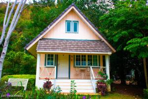 ein kleines rosafarbenes Haus mit blauen Fenstern und einer Veranda in der Unterkunft Cottages @ Hill Resort in Mu Si