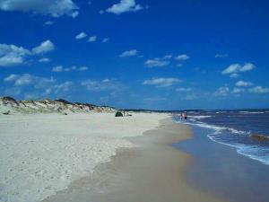a beach with people on the sand and the ocean at Lagomar Casa tipo loft in Ciudad de la Costa