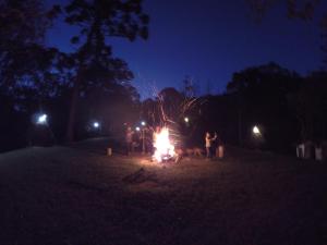 a group of people standing around a fire at night at Gran Camping Cabanas da Fazenda in Visconde De Maua