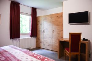 Schlafzimmer mit einem Bett, einem Schreibtisch und einem TV in der Unterkunft Sporthotel Spoegler in Klobenstein