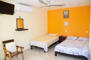 a bedroom with two beds and a tv and a chair at Casa Caridad del Cobre in Isla Mujeres