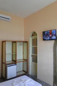Habitación con nevera y TV en la pared. en Ilhéus Hotel, en Ilhéus