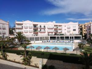 a large hotel with a swimming pool in front of it at Brisa Mar para 4 com piscina e WiFi in Luz