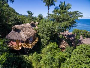 a resort with a thatched roof and the ocean at Xinalani Retreat Mexico in Qumiste