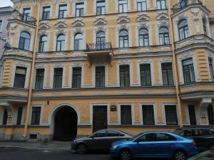 two cars parked in front of a large building at Apartment on Dmitrovskiy 7 in Saint Petersburg