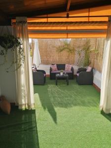 a patio with a couch and a table on grass at Ático Azahar in Córdoba