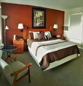 um quarto de hotel com uma cama grande e uma cadeira em Travellers Motel em Stratford