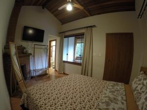 a bedroom with a bed and a tv on the wall at Cabanas da Fazenda in Visconde De Maua