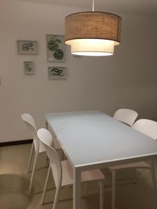 mesa de comedor blanca con sillas blancas y lámpara en DOS ORILLAS 413 BY GM RENTALS, en Colonia del Sacramento