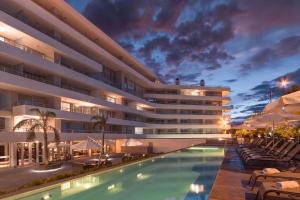 a hotel with a swimming pool in front of a building at DOS ORILLAS 413 BY GM RENTALS in Colonia del Sacramento