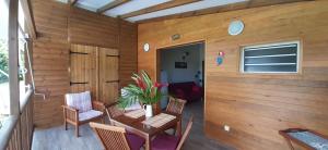 a room with a table and chairs and a wooden wall at Gite Manguier in Bouillante