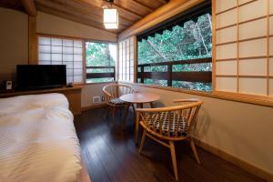 a room with a bed and a table and two chairs at KANSUIRO ANNEX in Hakone
