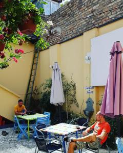 dois homens sentados à mesa num pátio com um guarda-chuva em Varad INN em Novi Sad