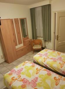 een slaapkamer met 2 bedden, een kast en een stoel bij Hotel-Cafe Knoors-Meeks Stein Urmond in Berg
