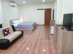 a room with a couch and a bed and a television at Na Cha Lae 1 ณ ชเล in Chanthaburi
