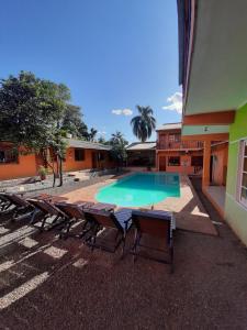 a swimming pool with chaises and chairs next to a building at Hostel Peter Pan in Puerto Iguazú