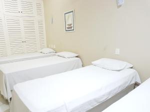 two twin beds in a room with white walls at OYO Del Verde Hotel in Itapecerica da Serra