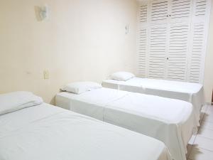 Cette chambre comprend 3 lits dans une chambre dotée de murs blancs et d'une fenêtre. dans l'établissement OYO Del Verde Hotel, à Itapecerica da Serra