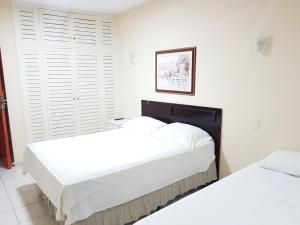 two beds in a bedroom with white walls at OYO Del Verde Hotel in Itapecerica da Serra