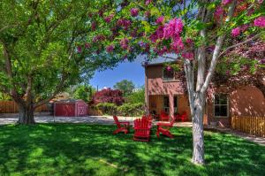 um quintal com cadeiras vermelhas e uma árvore com flores rosas em Cali Cochitta Vacation Rentals em Moab