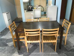 a wooden table with four chairs and a kitchen at Subang Ville Ehsan Apartment in Kampong Baharu Sungai Way