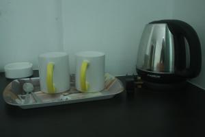 a coffee pot and three cups on a table at Citi Hotel in Miri