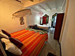 a bedroom with a bed with an orange and yellow comforter at Casalanka Hotel in Hikkaduwa