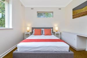 a white bedroom with a large bed with orange pillows at Barossa Idyll in Tanunda