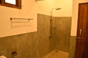 a bathroom with a shower with a glass door at Buddika Safari & Resort in Udawalawe
