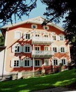 a large red and white building with a balcony at Villa Lageder in Sarntal