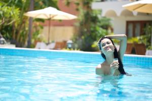 a woman in a swimming pool holding a cell phone at iRoHa Garden Hotel & Resort in Phnom Penh