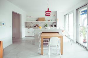 a white kitchen with a wooden table and white chairs at Le Canaillou par Dodo-a-Cassis in Cassis
