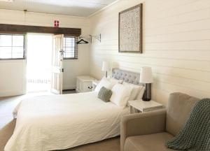 um quarto com uma cama branca e um sofá em Kaesler Cottages em Nuriootpa