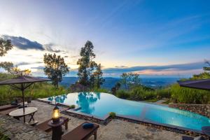 
a beach with a pool and a patio with a view of the ocean at Dream Cliff Mountain Resort in Haputale
